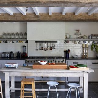 white kitchen with wooden ceiling beams and wooden table