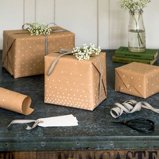3 boxed gifts, wrapped in brown wrapping paper with white dots and ribbons