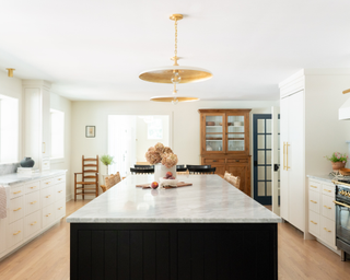 modern, cottage-style kitchen with marble-topped island, gold-plated light fixtures and wooden door