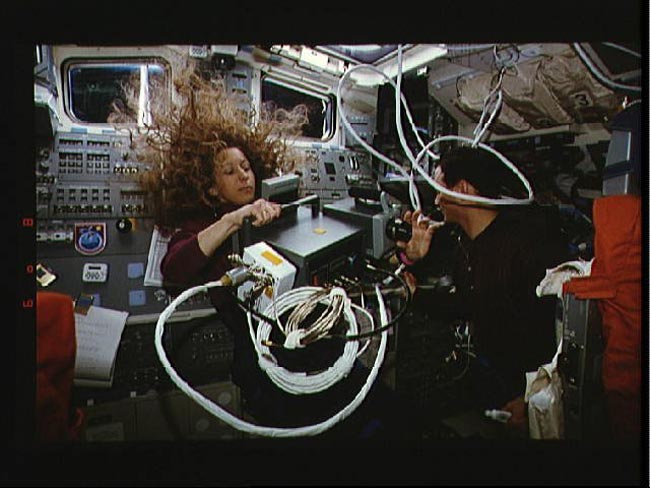 Astronaut Marsha Ivins works on the flight deck of the space shuttle Columbia as astronaut Pierre J. Thuot stands by to help, in this photo taken during the STS-62 mission in 1994.