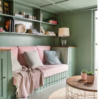 A built-in wooden sofa and shelving painted green in a country style house