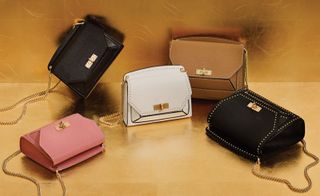 Different shaped and coloured handbags on a gold surface.