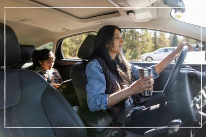 mum holding reusable coffee cup in car while daughter is in the back seat