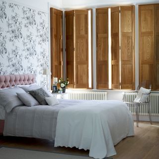 Bedroom with wooden shutters and neutral bed