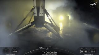 A black and white spacex falcon 9 rocket first stage sits on the deck of a ship at sea at night