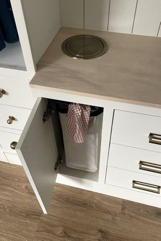 A kid's closet with an open cabinet revealing a DIY laundry chute