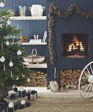 Christmas wall decor ideas with a pine cone garland hung over a fireplace with blue walls