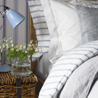 A bed with striped bed linen and matching wallpaper