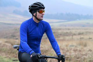 Man sitting on the top tube of a bike wearing a blue Madison DTE Isoler Thermal Long Sleeve Jacket