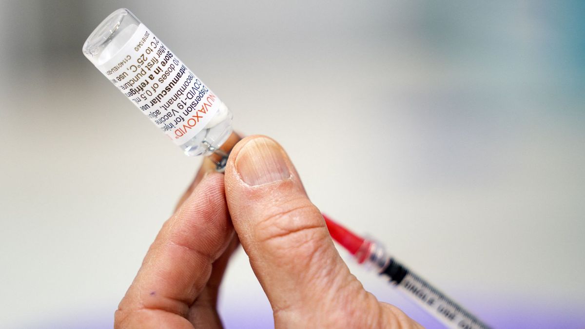 close up of a person&#039;s hand as they extract vaccine from a vial labeled &quot;novavax&quot;