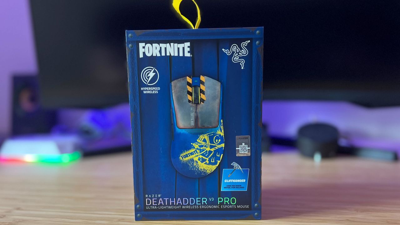 Razer DeathAdder V3 Pro Fortnite edition box on a wooden desk in front of PC setup