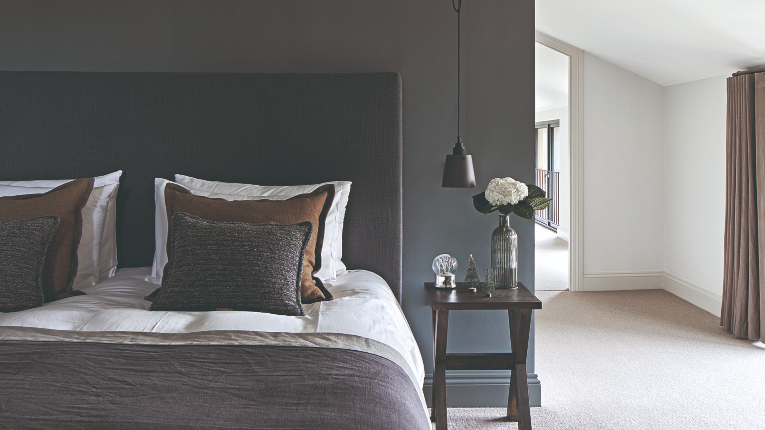 A bedroom with a feature wall painted in dark grey with the rest in stark white