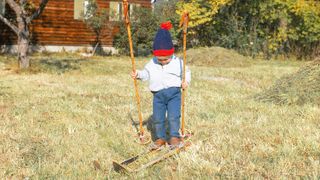 Child skiing in grass on sunny day