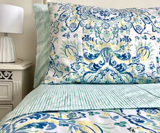 Martha Stewart Yasmin Duvet Cover on a bed beside a nightstand.