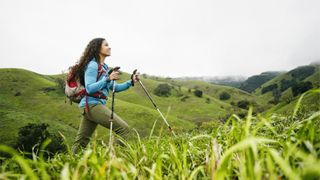 Smiling mixed race woman hiking with walking sticks