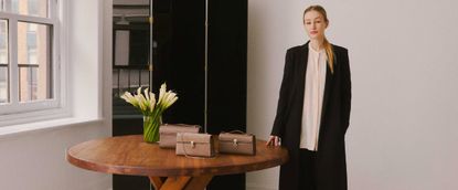 Amy Zurek poses for a photo next to a selection of handbags in Marie Claire's Women Who Win series