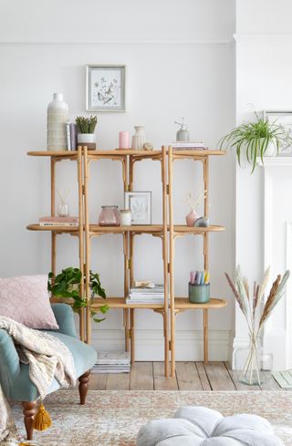 boho style rattan storage in living room, pink and grey accessories, duck egg blue velvet armchair, wooden floor, pampas