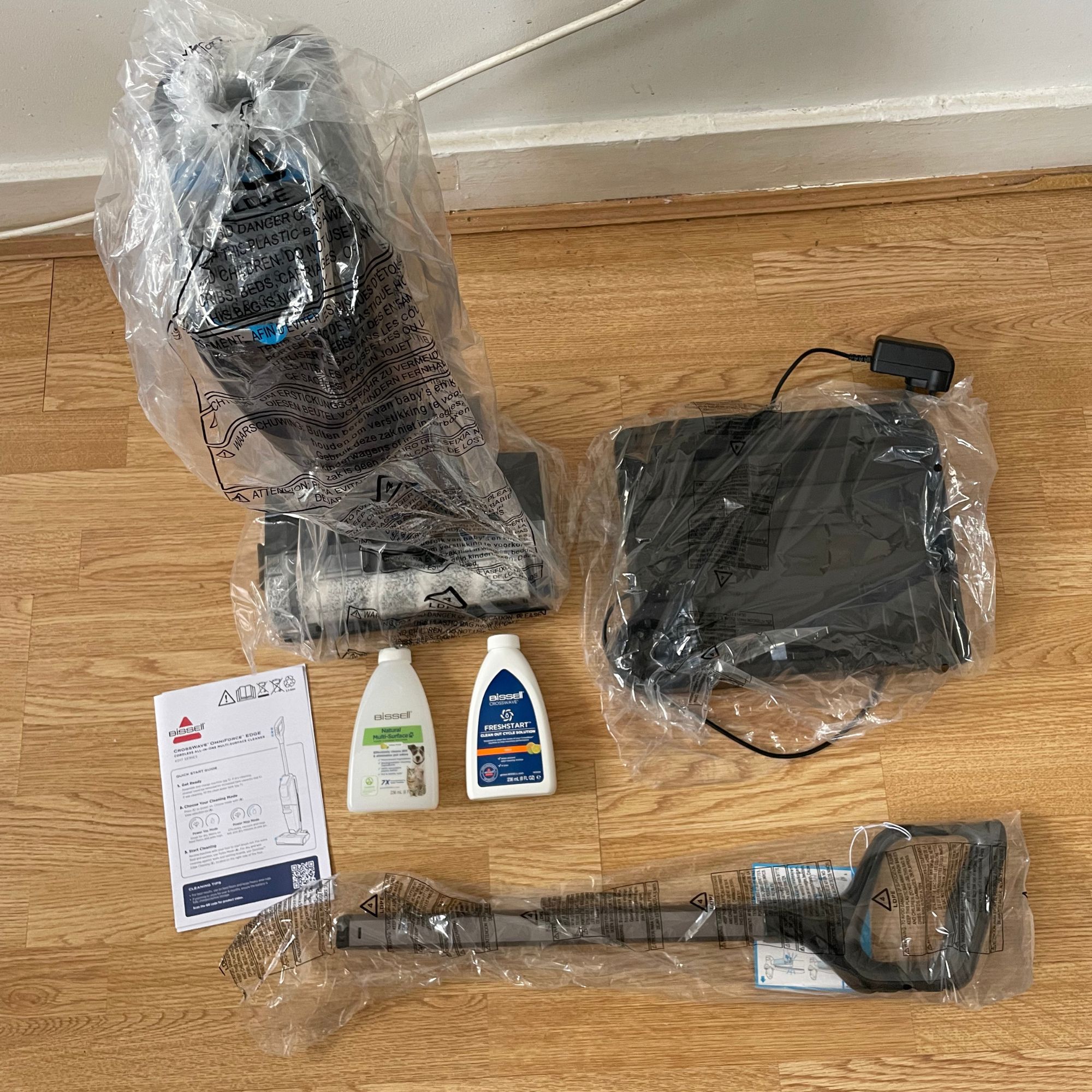 Components of the Bissell Crosswave Omniforce Edge wrapped in plastic and laying on the floor