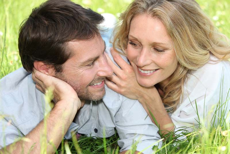 a man and woman lying in the grass smiling