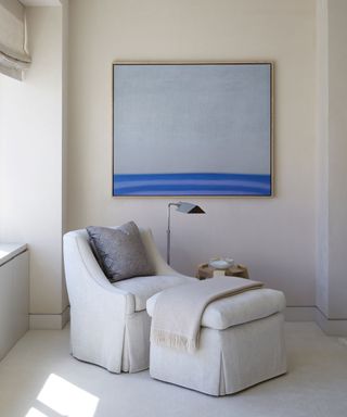 white armchair and footstool and blue artwork