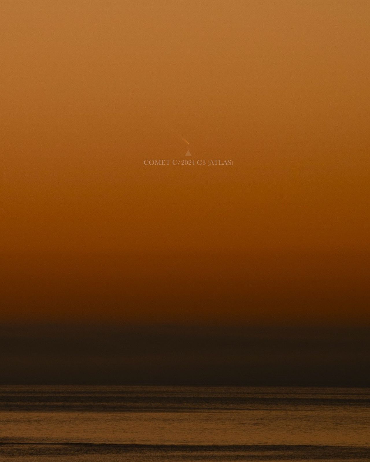 comet above water shining against a deep orange sky.