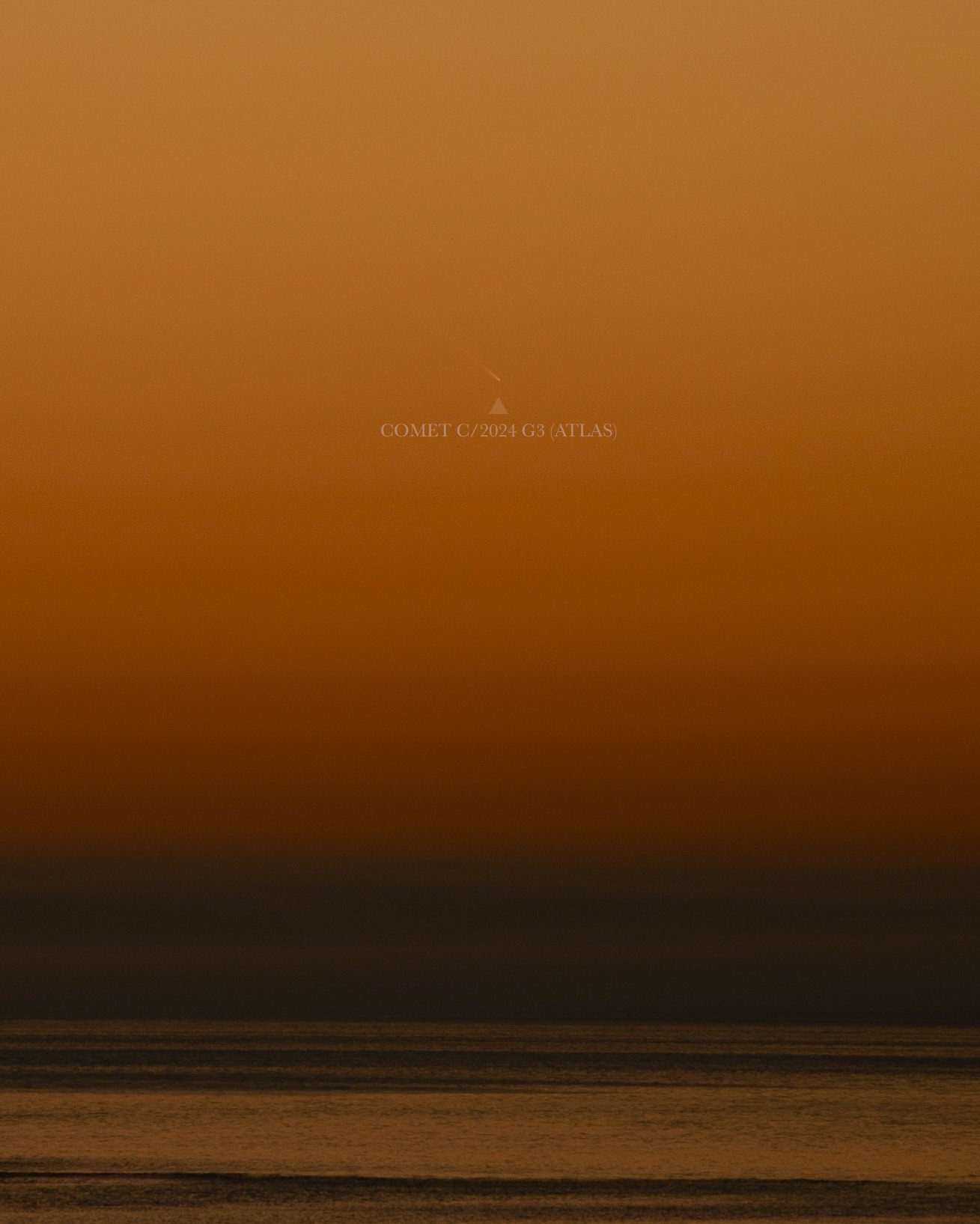 comet above water shining against a deep orange sky.