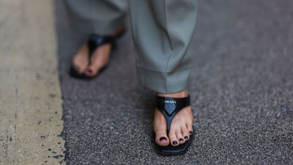 Woman wearing black nail polish and prada sandals GettyImages-1425997030
