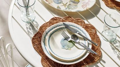 White outdoor patio table styled with shell-motif tableware