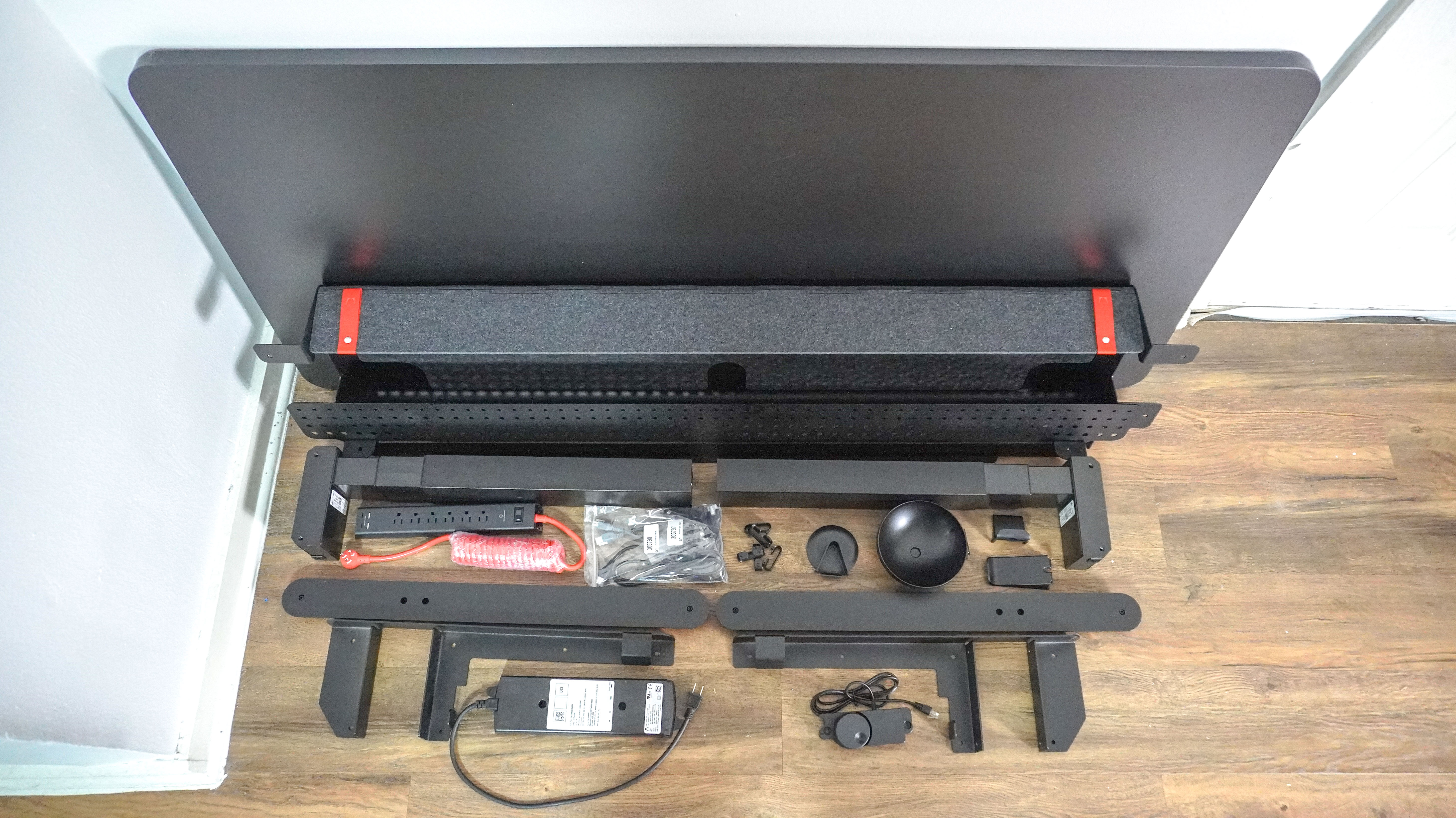 All of the parts that make up the Herman Miller Coyl Gaming Desk unboxed and laid out against a wall
