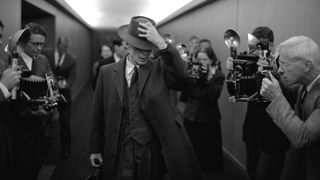 Cillian Murphy in the movie Oppenheimer, walking past press photographers (Universal Pictures)