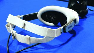 A photo of the Pimax Dream Air VR headset in white on a blue table. The headband, Pimax logo and the lenses are visible.