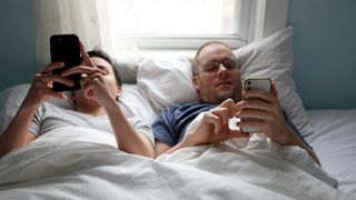 Two people in bed using their phones.