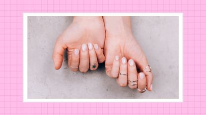 Lip gloss nails: Two hands with silver rings and a glossy, nude manicure/ in a pink template