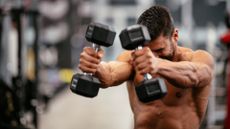 Man performing dumbbell front raises in a gym