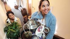 Two women moving into an apartment carrying boxes of possessions and household objects upstairs