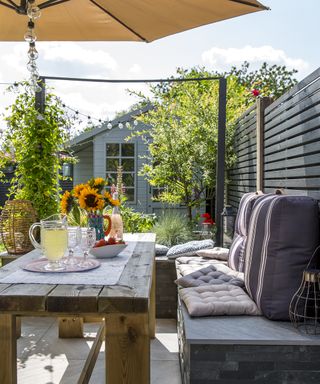 Shaded outdoor seating area with cut sunflowers in a vase and a shed in the background