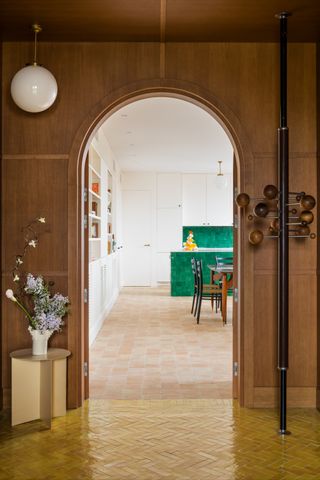 A room with yellow gloss floor tiles and matte terracotta floor tiles in the adjoining kitchen