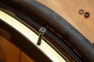 A valve stem half pushed through the taped rim on a tubeless wheel