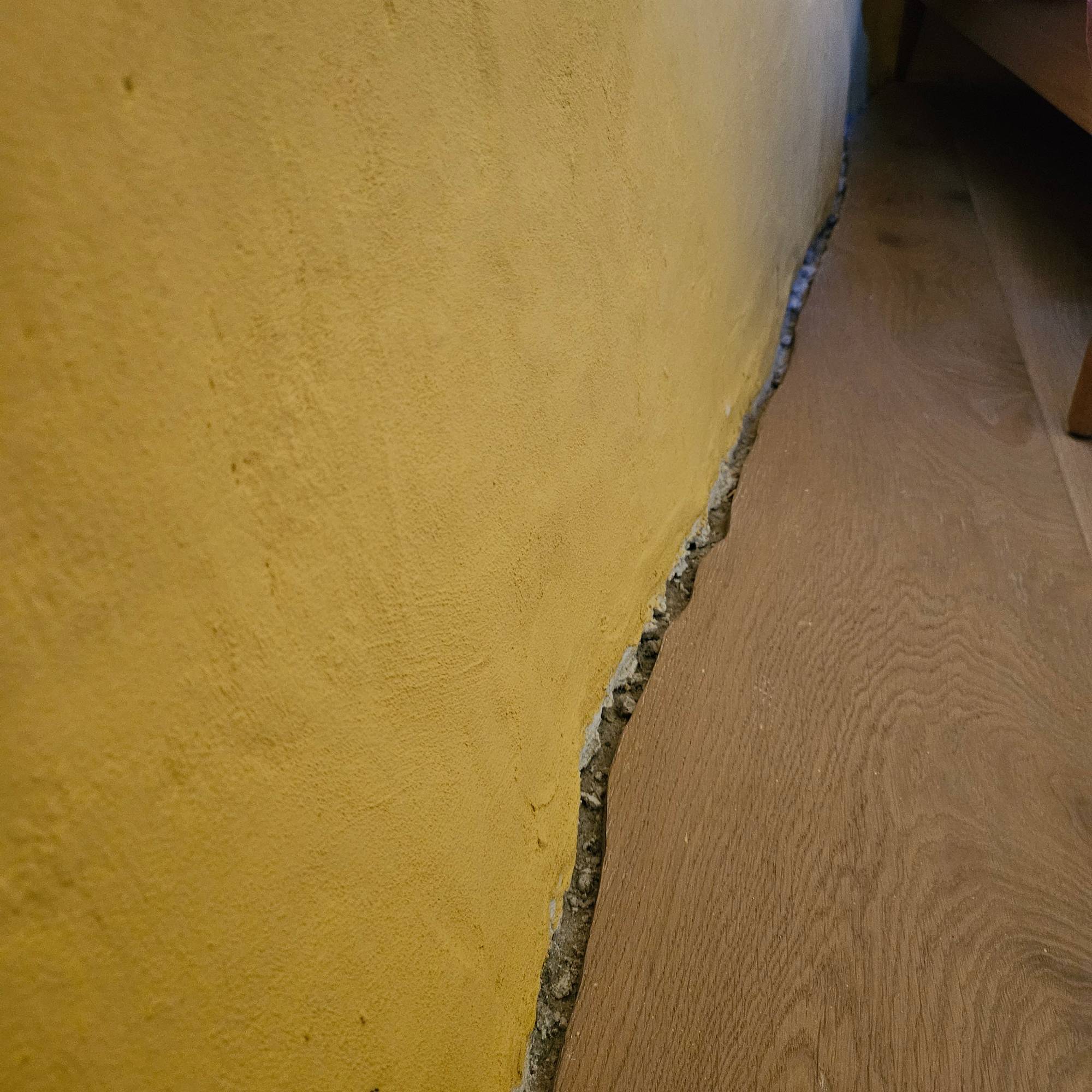 yellow lime plastered wall meeting wooden engineered flooring