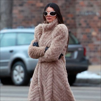 Kendall Jenner in a tan fur coat and white big glasses