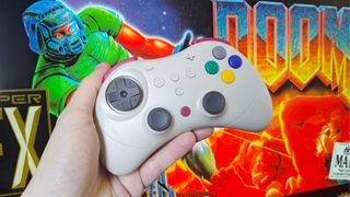 Hand holding Gulikit Elves 2 Pro controller in front of SNES DOOM box art.