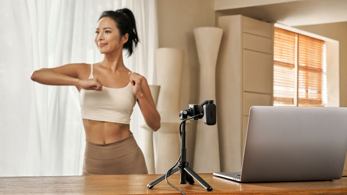 Insta360 Link 2 with woman exercising for the camera on a tripod and a laptop