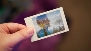 A hand holding a double exposure photograph on Instax Mini film