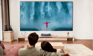 LG CineBeam HU915Q projector with man and woman watching