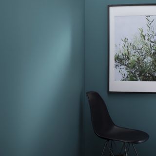 blue wall with artwork and black chair