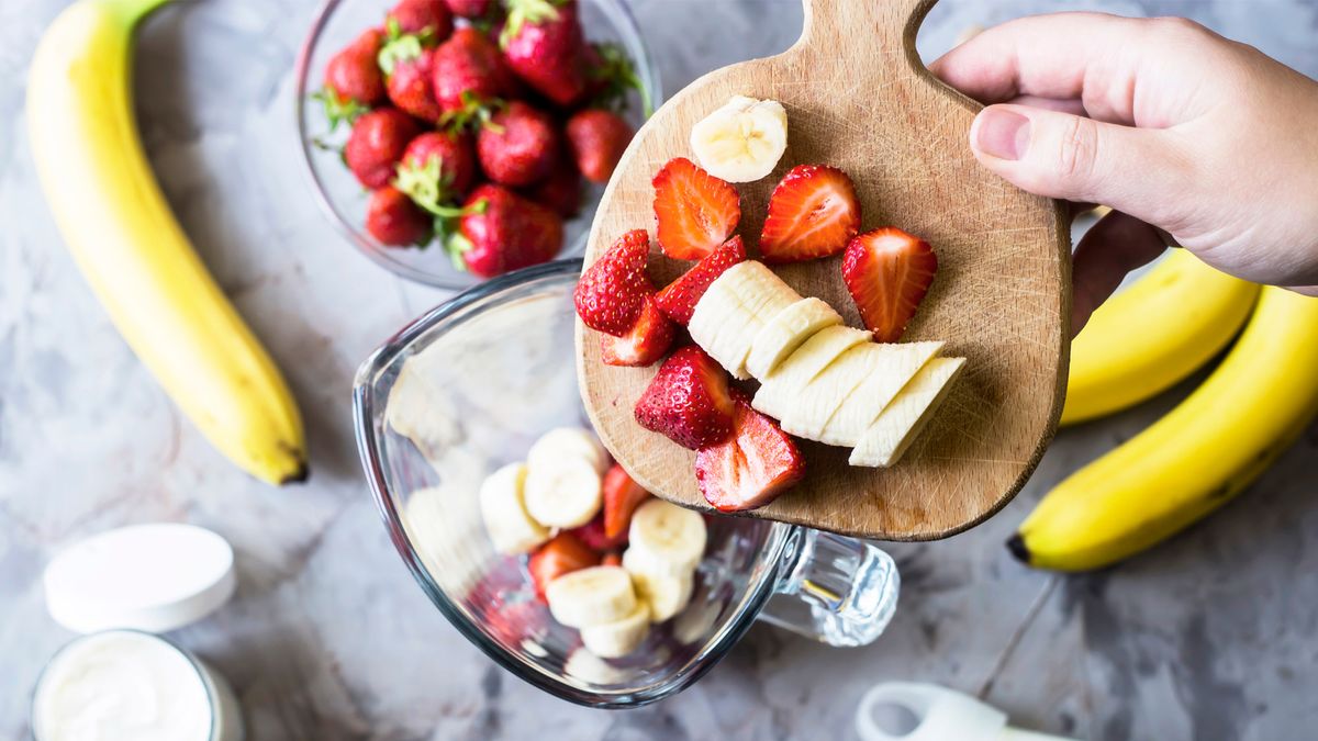 Fruit being added to a blender jug