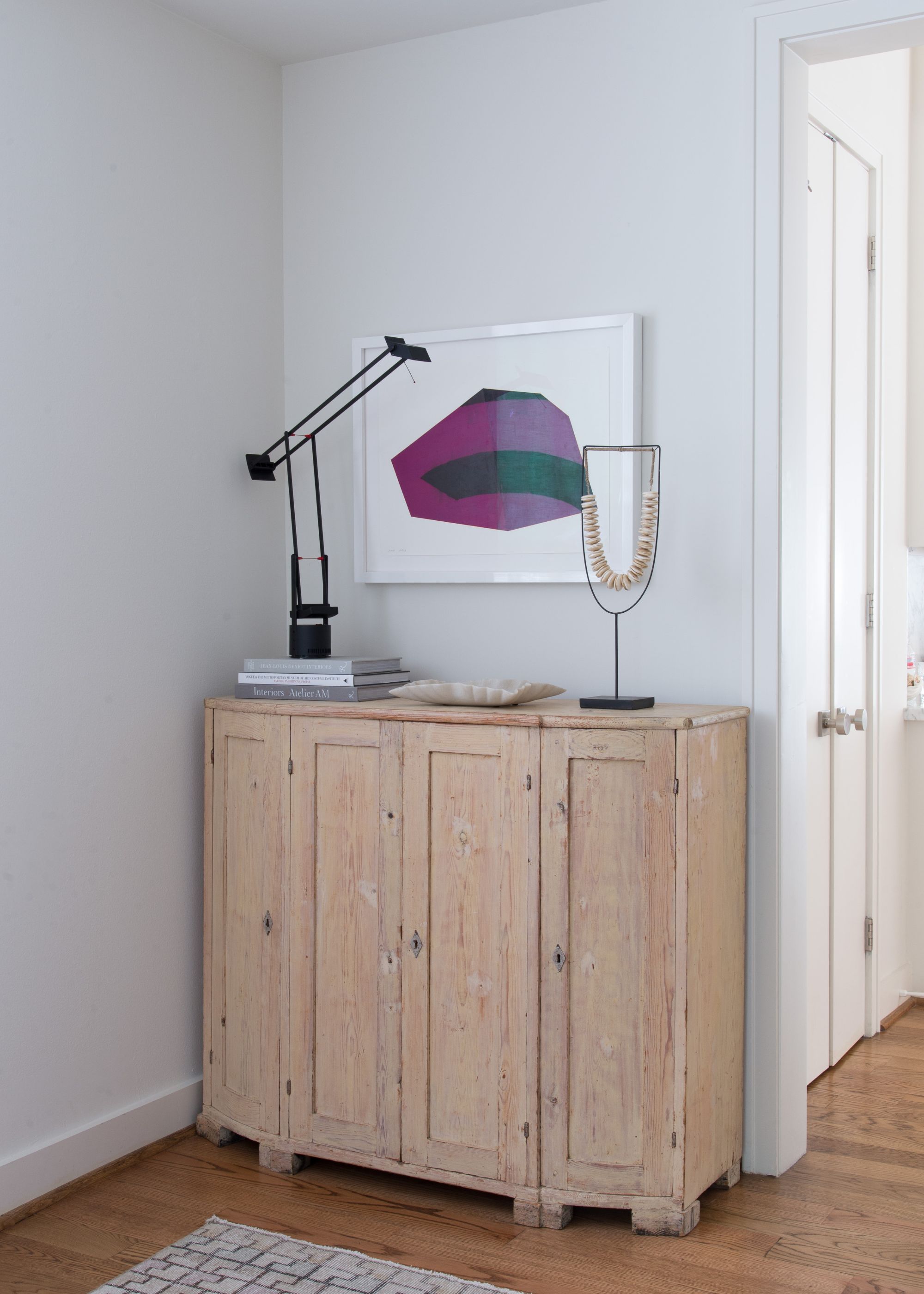 entryway with light gray walls, light wooden dresser with purple artwork above