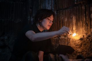 sophie thatcher as sister barnes lighting a match in a spooky basement in heretic