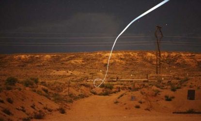 An LED light attached to a self-guided bullet reveals its path during a nighttime field test. 