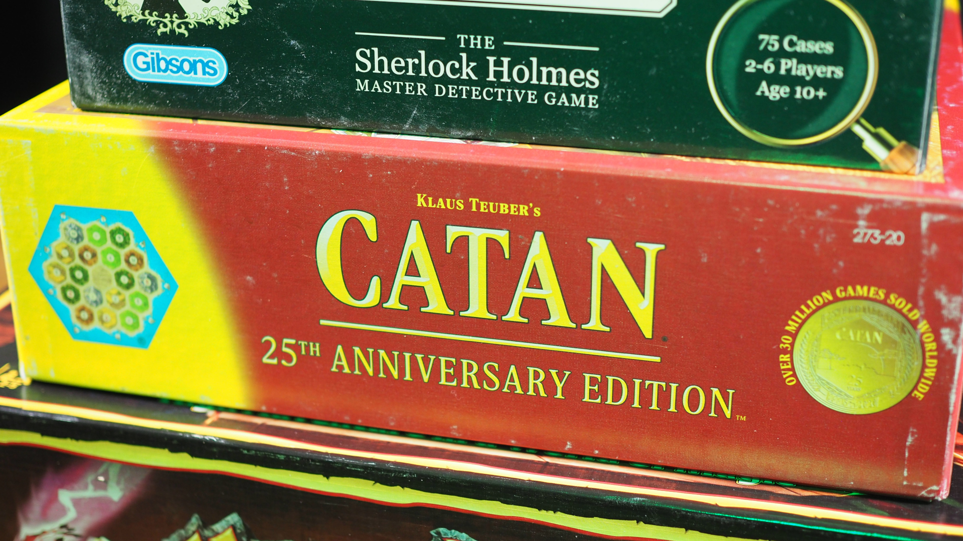 Catan 25th Anniversary Edition ditumpuk di atas HeroQuest, dengan 221b Baker Street di atasnya